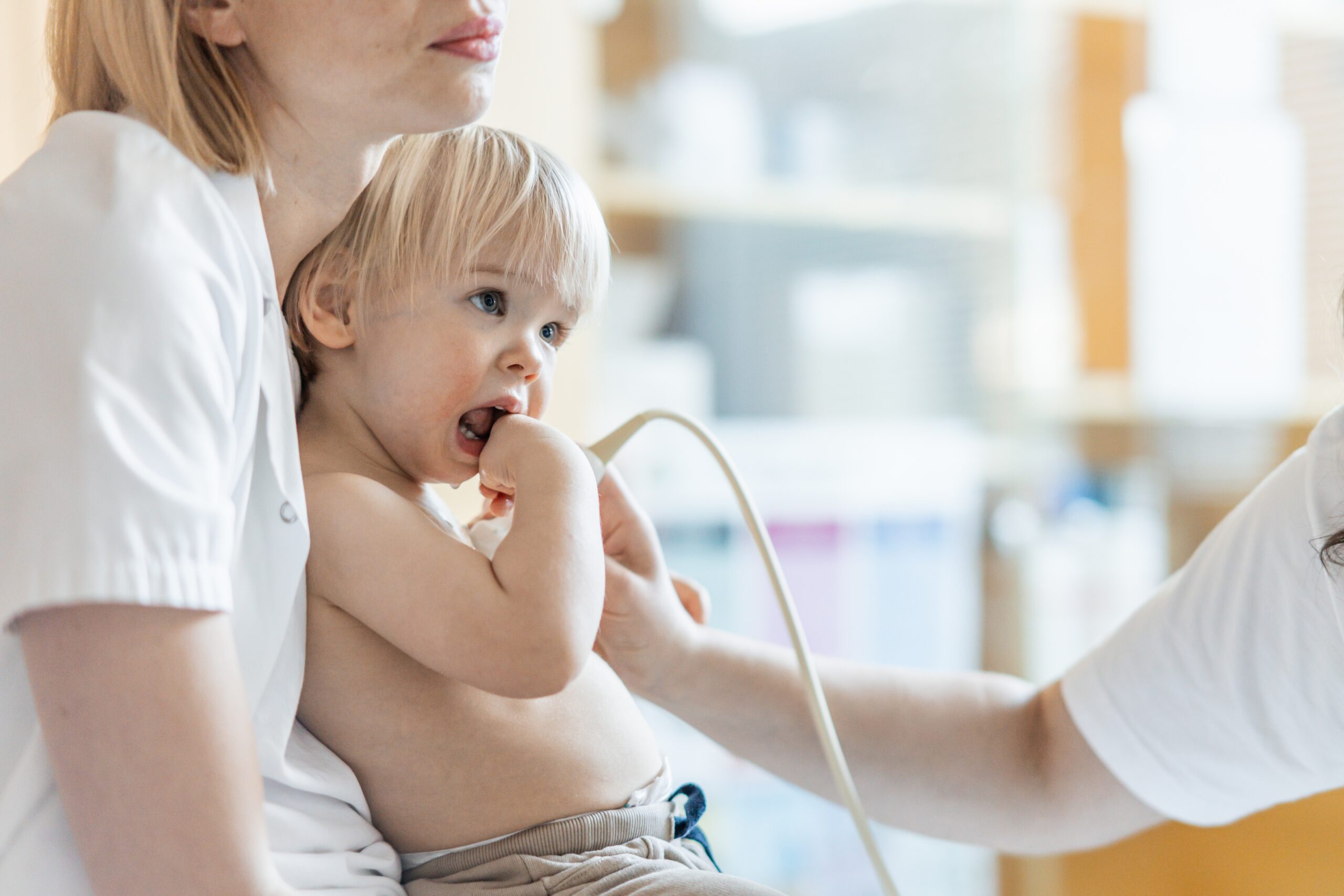 Small child being checked for heart murmur by heart ultrasound exam by cardiologist as part of regular medical checkout at pediatrician