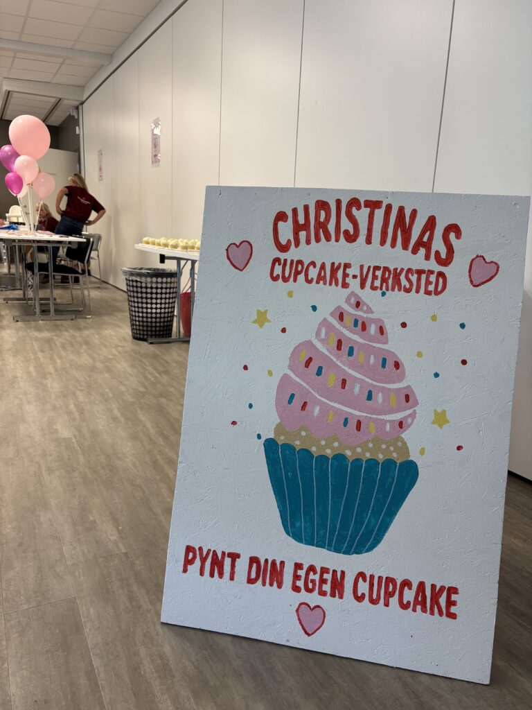 Et skilt med teksten «Christinas cupcake-verksted» står foran et bord med cupcakes.